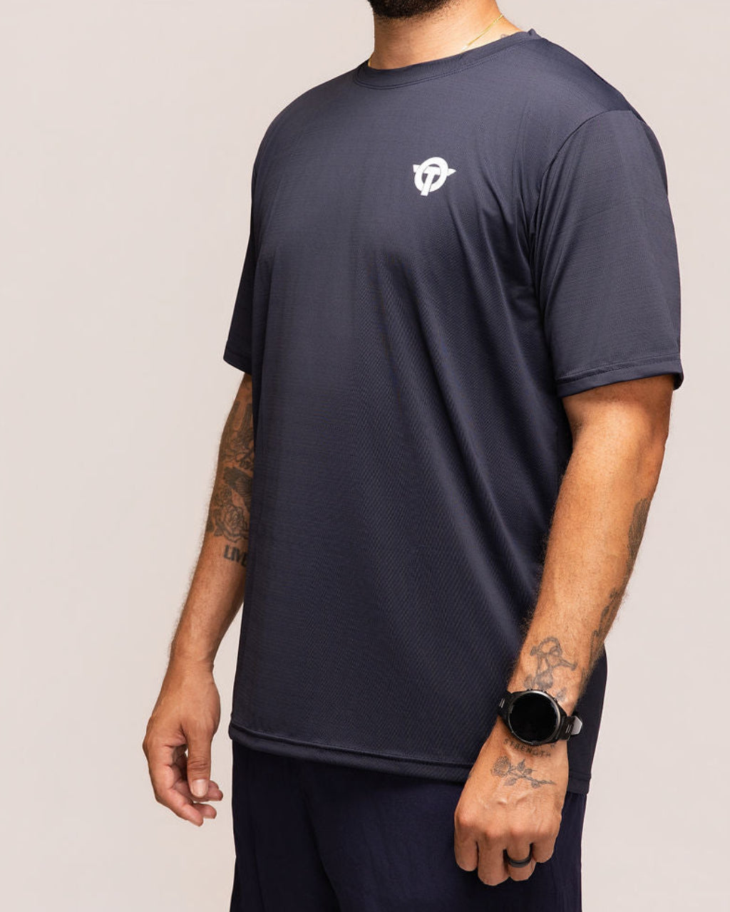 Man wearing a navy blue t-shirt and shorts with a logo on a plain background
